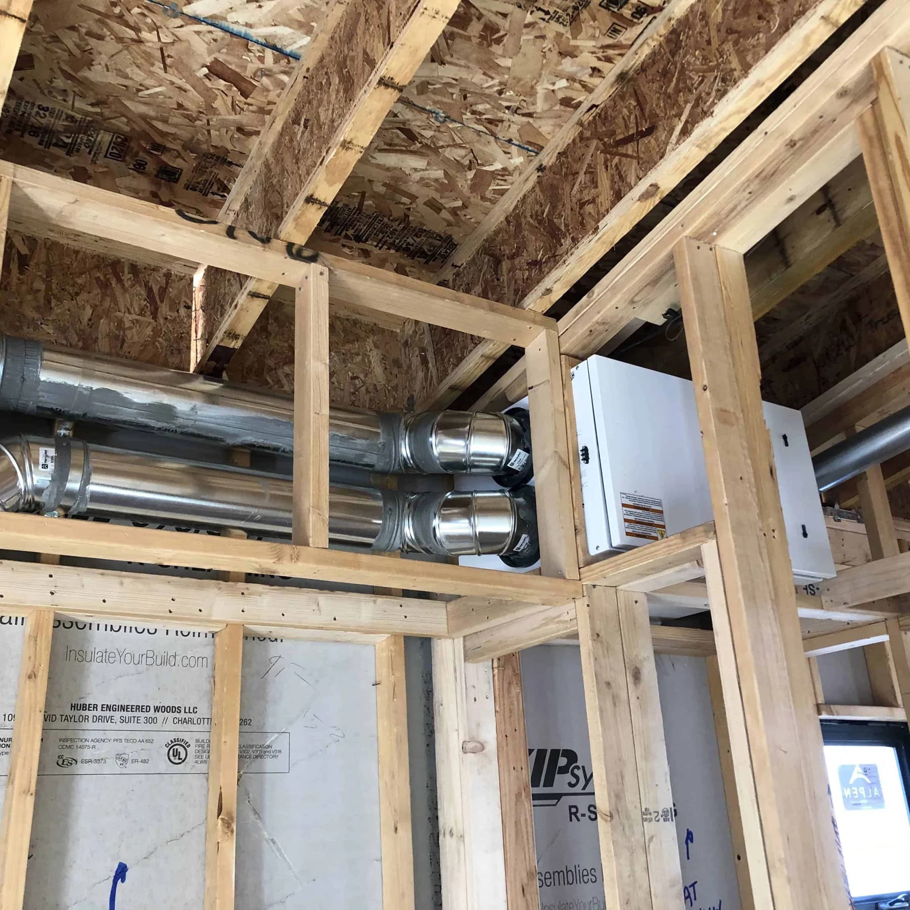 Metal ventilation ducts and equipment installed among exposed wood framing